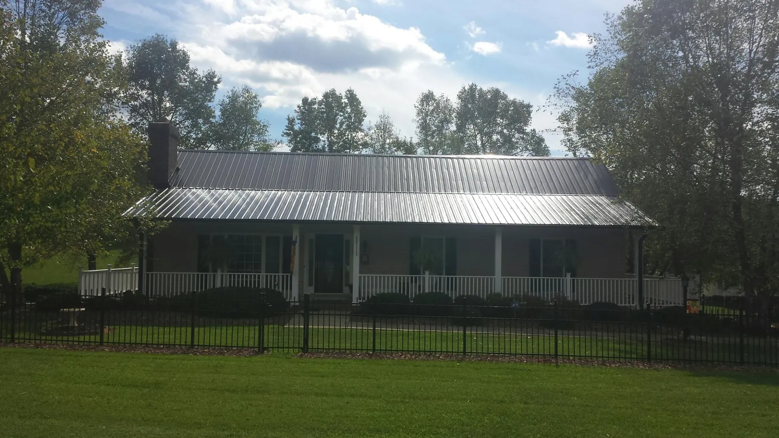 Gray metal roof on a brick ranch with a full width front porch — Gutter Guard Installation work by our crew in Nixon