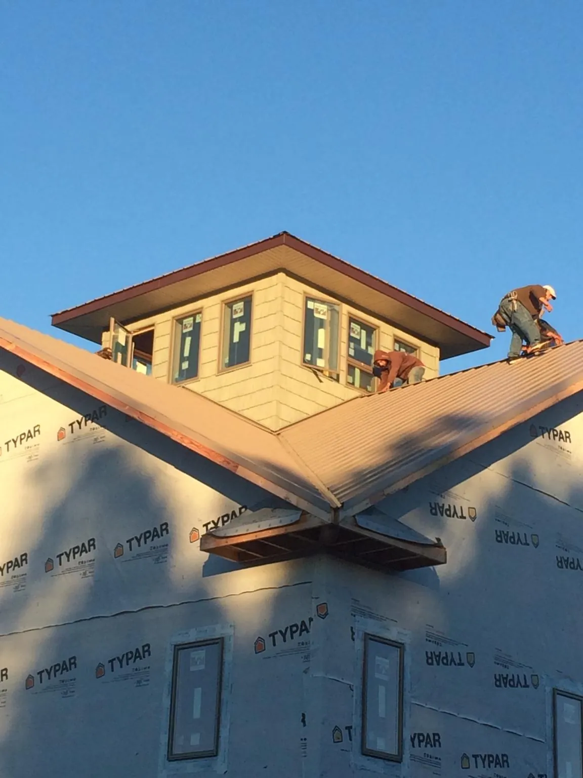 Roofers working around a rooftop cupola on a new metal roof at sunset — Roof Waterproofing in Nixon by Roofing Brothers